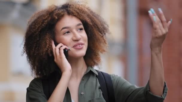 Etnia africana jovem mulher em pé ao ar livre desfrutar de conversa agradável no telefone. Compartilhe notícias com a família, resolva negócios remotamente. Tecnologia moderna e conceito de uso de conexão de operadora móvel — Vídeo de Stock