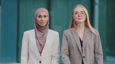 Bin yıllık kendine güvenen meslektaşları tesettürlü Hintli kız ve takım elbiseli beyaz kadın dışarıda çapraz kollarla poz veriyorlar. Başarılı iş kadınları, kadın takım konsepti.