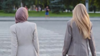 Genç, yetişkin, modern iş kadını iş arkadaşı ya da kız arkadaşı, Avrupalı, uzun saçlı, beyaz, sarışın kadın ve yaya geçidinde tesettürlü Hintli bir kız. İki kız öğrencinin arka planı