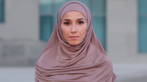 Retrato femenino al aire libre de cerca chica islámica musulmana joven mujer adulta mujer étnica vistiendo hijab beige ropa tradicional mirando a la cámara de pie posando en la calle ciudad tranquila expresión facial — Vídeo de stock