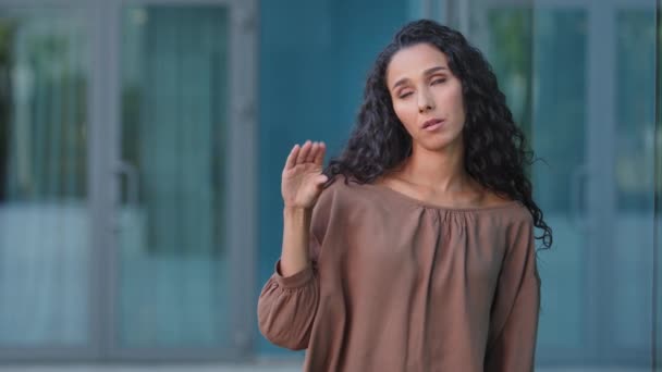 Retrato al aire libre hispano aburrido mujer decepcionada chica mirando la cámara que muestra bla-bla-bla gesto de las manos y los ojos ondulados aislados en el fondo del edificio de la ciudad. Promesas vacías, bla lier concepto — Vídeo de stock