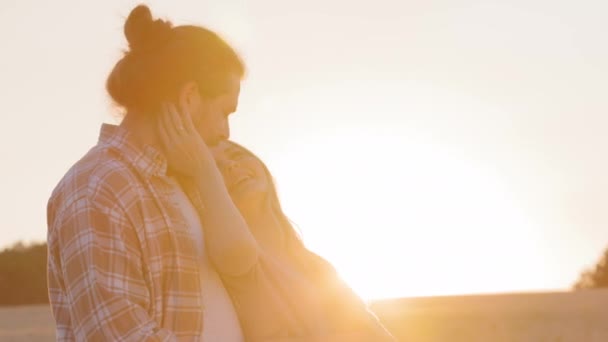 Szczęśliwy nowożeńcy dwie sylwetki ludzi biały młody para brodaty mężczyzna i uśmiechnięta kobieta mąż i żona małżonkowie chłopak i dziewczyna stoją na polu o zachodzie słońca w promienie słońca przytulanie przytulanie — Wideo stockowe