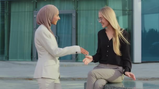 Amigável sorrindo colegas milenares menina indiana em hijab e jovem mulher europeia cumprimentando uns aos outros por aperto de mão. Recrutador ou gerente tremendo bem sucedido mão empresária oriental na reunião — Vídeo de Stock