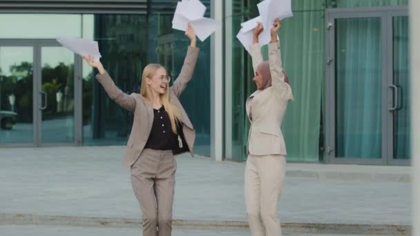 Verheugd diverse vrouwelijke ondernemers veel plezier vieren succesvol project samen, gelukkig opgewonden multiraciale collega 's, meisje in hijab dansen lachen met papierwerk, vrijdag viering concept — Stockvideo