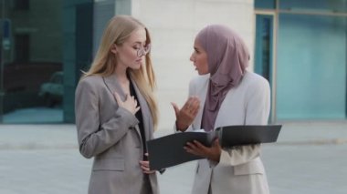Başörtüsü içindeki genç Hintli kadın hatalar rapor etti, kızgın stajyer Avrupalı genç kızı azarladı gözlüklü. Beyaz kadın ofis çalışanı. Yanlış belgelediğim için özür dilerim.