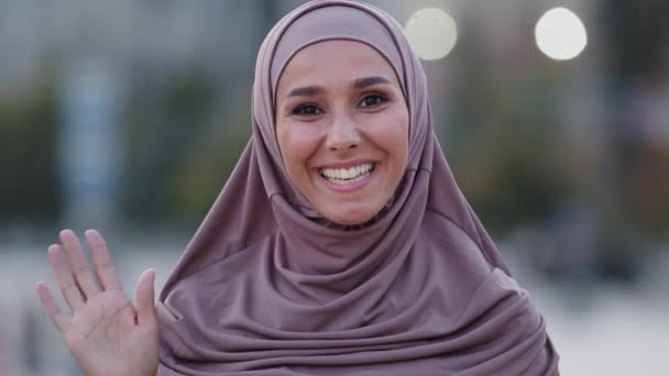 Női portré szabadban iszlám lány fiatal felnőtt muszlim nő barátságos mosolygós hölgy diák visel bézs hidzsáb mosoly helló kéz üdvözlő beszéd beszélgetés beszélgetés online chat konferencia videó hívás — Stock videók