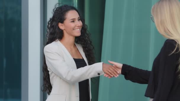 Happy diverse female colleagues or partners shake hands get acquainted at meeting. Smiling multiracial businesswomen handshake client and agent greeting gesture. Two people expressing respect concept — Stock Video