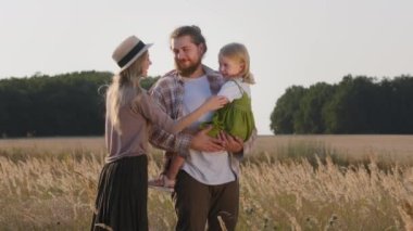 Buğday tarlasında yaşayan beyaz çiftçi ailesi. Yetişkin baba sakallı baba kucağında küçük kız çocuğu, şapkalı anne akrabalarına sarılıp çocuğun kafasını okşuyor.