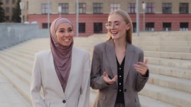 Gülümseyen genç Avrupalı Kafkas kadın yöneticisi tesettürlü Hintli kızla iletişim kuruyor. Mutlu iş kadını Doğulu müşteriyle görüşüyor, proje detaylarını dışarıda tartışıyor.