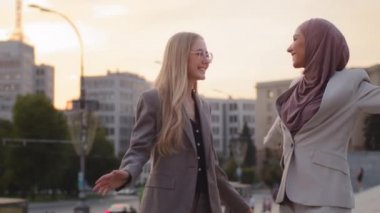 Başarılı bir anlaşmadan sonra tesettürlü genç beyaz iş kadınları ve dans eden kız. Çeşitli mutlu çalışan enerjisi ara vermek ve dinlenmek için hareket ediyor. Tasasız, çok ırklı kadın iş ekibi.