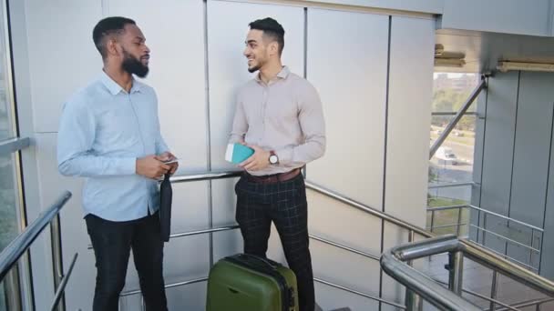 Dva obchodní muži multiraciální kolegové multiethnic spolupracovníci hispánský muž a afro Američan chlap stojící v terminálu letiště mluvit diskutovat, aby vysoké pět rukou gesto unie znamení týmová práce symbol — Stock video