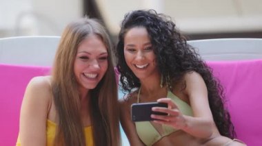 Çeşitli İspanyol beyaz kız arkadaşlar yaz havuzu ile güneşleniyor arkadaşlarıyla ya da aileleriyle iletişim kuruyor cep telefonuyla zoom uygulaması kullanıyor, keyifli sohbetler yapıyor, uzaktan konuşuyor.