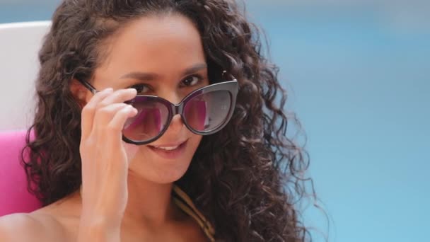 Headshot portrait of happy cheerful curly Hispanic girl student takes off sunglasses, looks at camera, winks happily smiling. Millennial carefree lady with white toothed smile enjoying summer vacation — Stock Video