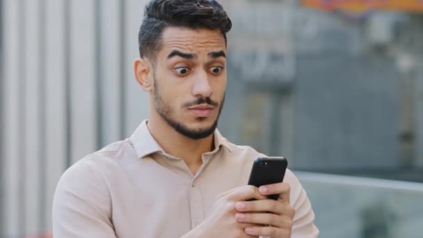 Hispano sorprendido hombre de negocios recibir SMS mensaje ofrecen oportunidad, árabe feliz hombre leyendo buenas noticias en el teléfono inteligente. Emocionado ganador masculino alegre al aire libre celebrando el éxito de la victoria del teléfono móvil — Vídeos de Stock