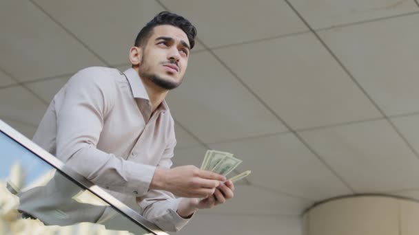 Bottom view pensive hispanic young successful business man arab boss ceo manager rich guy bearded leader holding dollars money feeling doubts thinks about investments financial problems bank debt — Stok Video