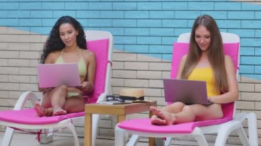 Bilgisayarla çalışan başarılı, çok ırklı, Kafkas kökenli İspanyol serbest blog yazarları tatillerde havuz kenarında el hareketlerinin keyfini çıkardıklarını gösteriyor. Hareket özgürlüğü, yaratıcı meslek