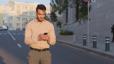 Şehir merkezindeki şık sakallı İspanyol işadamı cep telefonu mesajlaşma, kaydırma uygulaması teknolojisi kullanıyor. Akıllı telefon ile iletişim kuruyor ve cihaz ile sohbet ediyor.