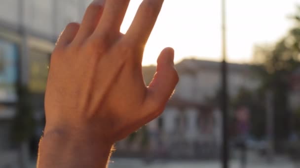Unrecognizable young adult man guy stretches out male hand in sun in city faith in God dream religion. Close up palm on sunny sunbeams sunset sunrise background outdoors in street enjoy nature sky — Stock Video