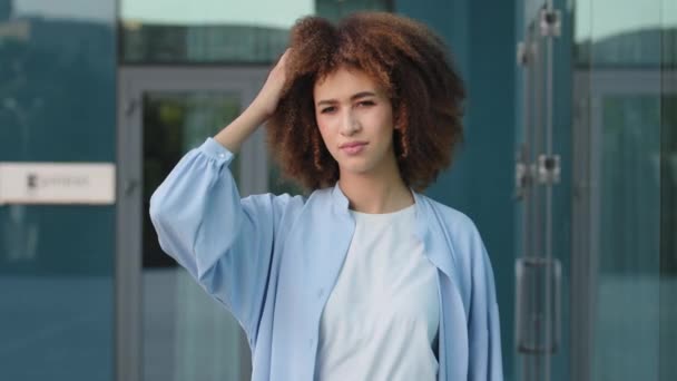 Afro Américaine fille songeuse femme étudiante gratte la tête en pensant à l'idée se souvenir de la mémoire froncements de sourcils visage réfléchissant en regardant la caméra haussements d'épaules répondre se sent incertain doutes indifférence — Video