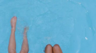 Yakından bakınca iki çift esmer, ince, güzel kadın bacakları sallanıyor ve mavi yaz yüzme havuzunda dalgalanmaya başlıyor. Bayan turist ayağı kaplıcada, hafta sonu tatil beldesi havuz başında.
