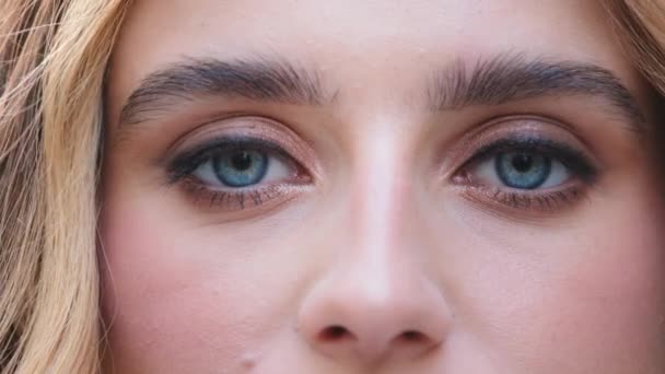 Gros plan de visage féminin jeune fille caucasienne regardant la caméra avec de beaux yeux bleus, jolie dame jolie avec une bonne vision vue avec de longs cils maquillage naturel, ophtalmologie — Video