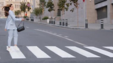 Siyah çantalı, beyaz, modaya uygun, beyaz, beyaz bir kadın yaya geçidinde yürüyor, yaya geçidinde yürüyor, yaya geçidinde yürüyor, trafikte zıplıyor, yürüyor.
