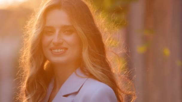 Porträt der schönen erfolgreichen jungen erwachsenen Geschäftsfrau kaukasischen Millennial hübsches Mädchen weibliches Modell mit langen Haaren steht im Freien in der Stadt attraktives Gesicht in Sonnenstrahlen vor dem Hintergrund der Sonnenuntergangssonne