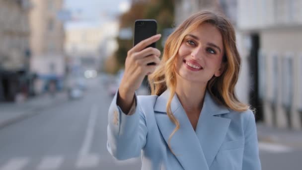 Retrato de la joven hermosa chica Caucásico mujer de negocios blogger modelo vlogger se para en la ciudad tiene teléfono tomar fotos en rodajes de cámara móvil video para vlog blog con teléfono inteligente llamada de chat en línea — Vídeos de Stock