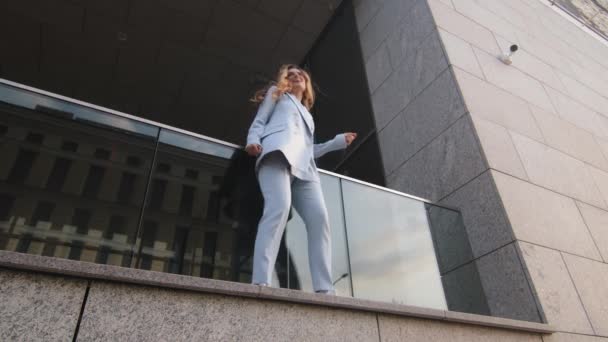 Bottom view funny caucasian successful business woman student girl in stylish suit manager worker stands on balcony terrace near office building of company dancing dance actively moving having fun — Stock Video