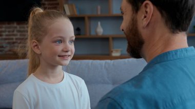 Evde mutlu beyaz bir aile babası tatlı kızıyla konuşuyor birlikte gülümsüyor babasıyla konuşuyor sevimli çocuk kızıyla iletişim kuruyor çocuk bakımı velayeti ile ilgili eğlenceli sohbetler yapıyor.