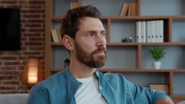 Evdeki beyaz adamın portresi ciddi bir şekilde kameraya bakıyor. Evin içinde, rahat bir oturma odasında orta yaşlı, sakallı, kendine güvenen, kendine güvenen bir erkek. Kanepede dinlenen ev sahibi.