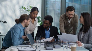 Çok kültürlü iş adamları Afro-Amerikan Kafkasyalı Hintli erkekler ofiste konuşuyorlar kağıtları analiz ediyorlar iş adamları iş adamları şirket işverenleri hakkında tartışıyorlar.