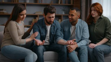 Dört çok ırklı arkadaş, evde oturan üzgün adamı destekliyor. Endişeli erkek, sağlık sorunları, iflas sorunları, ayrılık sorunları, destek veren kadın grubu.