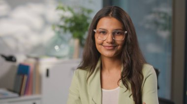 Gülümseyen kendine güvenen güzel Hintli iş kadını yalnız çalışıyor Arap kadın iş kadını pozu veriyor pazarlama müdürü Hindu bayan projeci kameraya bakıyor.