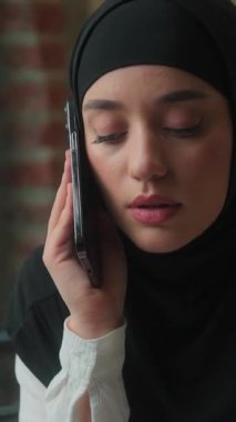 Ciddi Müslüman iş kadını Arap İslami iş kadını tesettürlü kadın yönetici girişimci danışman yönetici. Ofiste konuşan akıllı telefon konuşmasına cevap veriyor.