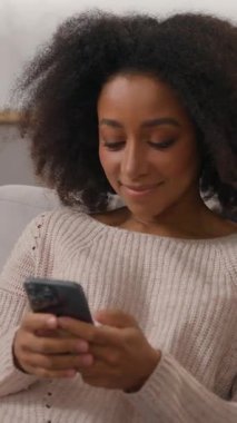 Neşeli, neşeli, bağımlı, Afro-Amerikan kadın, cep telefonu kullanan, akıllı telefon kullanan, sohbet eden, internette gezinen, internet üzerinden alışveriş yapan mutlu bir cihaz.