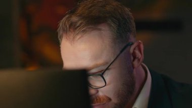 Karanlık ofiste çalışan bir işadamı bilgisayar ekranına bakarak notlar yazıyor son teslim tarihine kadar iş adamı Kafkasyalı erkek programcı gece fazla mesai yapıyor.