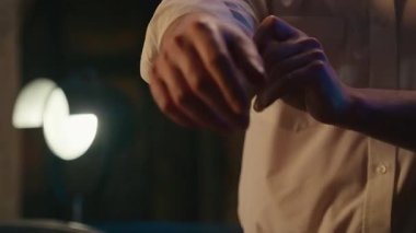 Tanınmayan iş adamı kollarını sıvayıp yaka gömleğini düzeltiyor. Akşam işi bitiyor. İş günü ofiste tekstil stili, şık iş adamı kıyafetleri hazırlıyor.