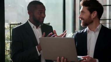 İki heyecanlı iş adamı dizüstü bilgisayar ekranı seyreden iş adamları ofiste iyi bir fikir hakkında konuşuyorlardı. Mükemmel sonuç projesi başarısı Kafkas asıllı Afrikalı Amerikalı iş arkadaşlarını neşelendirdi.