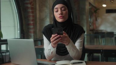 Akıllı telefon tutan düşünceli Müslüman iş kadını daktilo sohbeti yapmayı düşünüyor. İş kadını İslamcı kadın tesettürlü kız çalışan yönetici şirkette çalışan cep telefonu internet uygulaması kullanıyor.