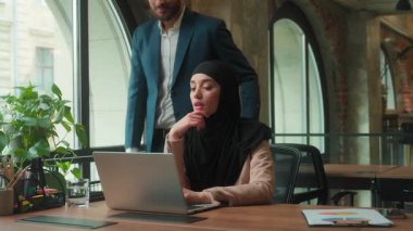 Müslüman iş adamları intörn Arap kadın dizüstü bilgisayarda çalışan Hintli işadamı patron iş kadınına bilgisayar işinde tavsiyelerde bulunmaya geliyor iki ofis ortağı yönetici iş arkadaşı ortaklığı