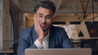 Sıkıcı, motivasyonsuz Arap iş adamı. Ofiste dizüstü bilgisayarda çalışan, sıkıcı bir işte çalışan, bilgisayarcı, yorgun, bıkkın, bunalımlı, bunalımlı, bıkkın bir erkek.