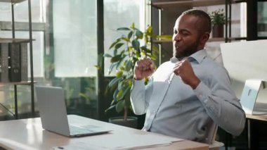 Gülümseyen Afrikalı Amerikalı işadamı internette dans ediyor. Bilgisayarda erkek, olgun iş adamı şirket CEO 'su. Eğleniyor, eğleniyor, iyi iş çıkarıyor.