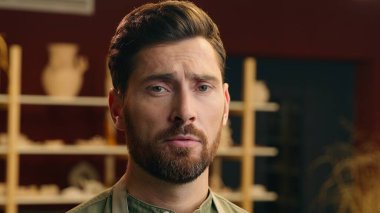 Mutsuz, üzgün, Kafkasyalı, küçük işletme sahibi, erkek, depresif, girişimci, çömlekçi, çömlek atölyesinde kamera üzüntüsü ve stres ifadesine bakan sanatçı.