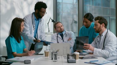 Endişeli çok kültürlü beş kişi Kafkas Hindistanlı Afrikalı kadın erkek hemşireler hoşnutsuz doktor lideri hasta sonuçları zor sağlık kontrolü sorununu tartışıyor