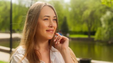 Avrupalı bir kadın dudaklarını ısırıyor gülümseyerek flört ediyor yüz ifadesini çekici güzellik şehrini işaret ediyor moda duygusal park kadınlarıyla iletişim kuruyor pozitif beklenti içindeki kız.