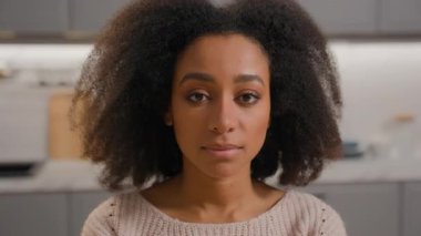 Kapalı portre güzel kız yüzü ev mutfağındaki Afro-Amerikan kadına bakıyor ciddi bakışlar atan kadın yüz ifadesi kıvırcık saç stili sağlıklı cilt güzelliği