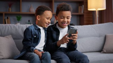 İki Afro-Amerikalı çocuk cep telefonu kullanıyor, akıllı telefonlarıyla eğleniyorlar. İki küçük çocuk, iki pozitif aile kardeş, çocuklar, ebeveynleri tarafından kontrol edilmeyen, gülen mutlu bir çocukluk.
