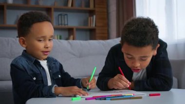 İki Afro-Amerikalı çocuk resim çiziyor. Psikoloji resim terapisi evde, oğullarda, kardeşlerde arkadaşlar. Çocuklar renkli çizimlerle apartman dairesi etnik aile sanat eğitimi alıyorlar.