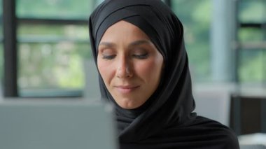 Arap iş kadını tesettürde bilgisayarla çalışıyor Hintli Müslüman iş kadını dizüstü bilgisayar kullanıyor ekranda gülümseyen İslamcı kadın çalışana bakın internet profesyoneli ile çalışıyor